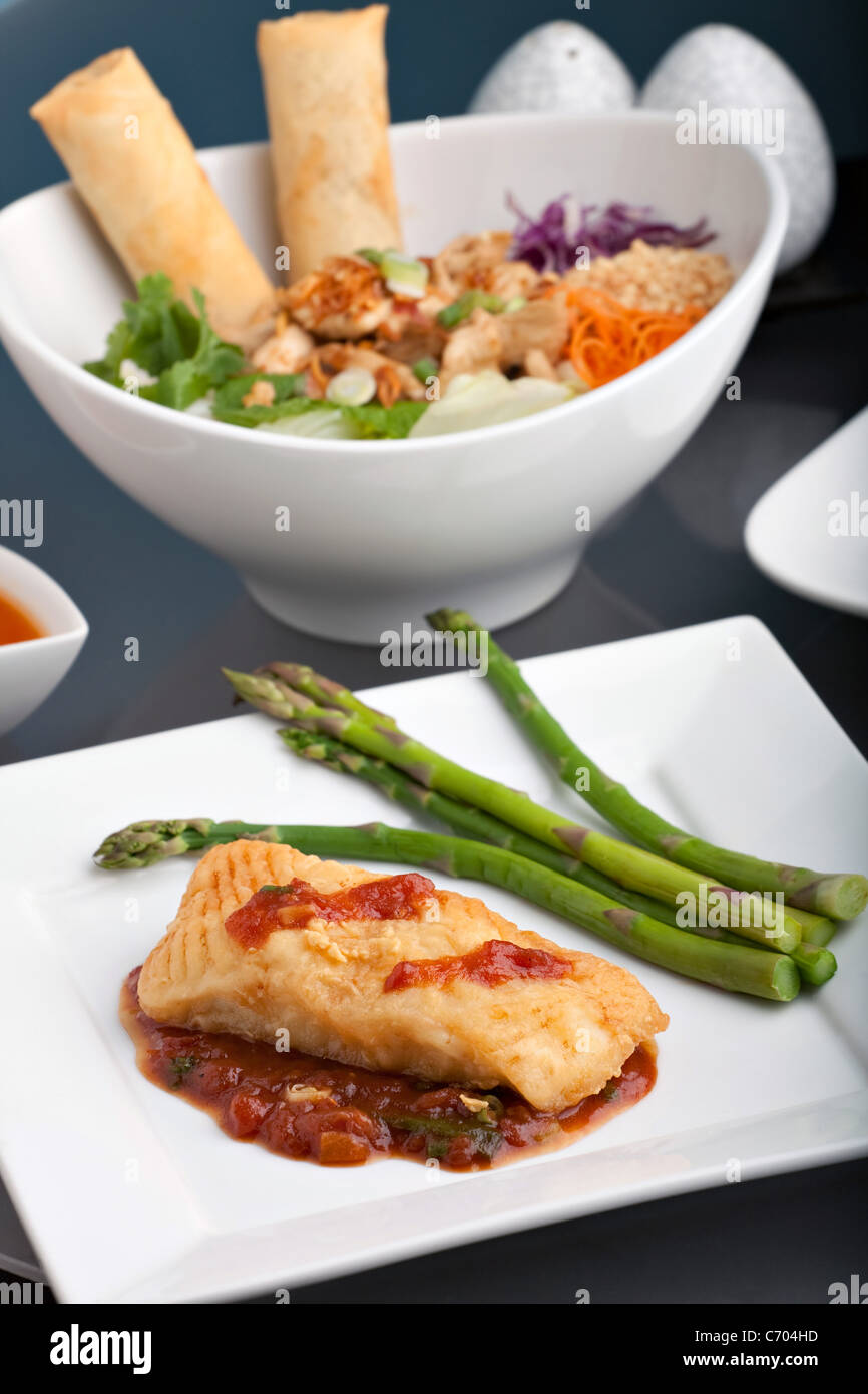 Freshly prepared Thai style sea bass fish dinner with asparagus and appetizer with a contemporary presentation. Stock Photo