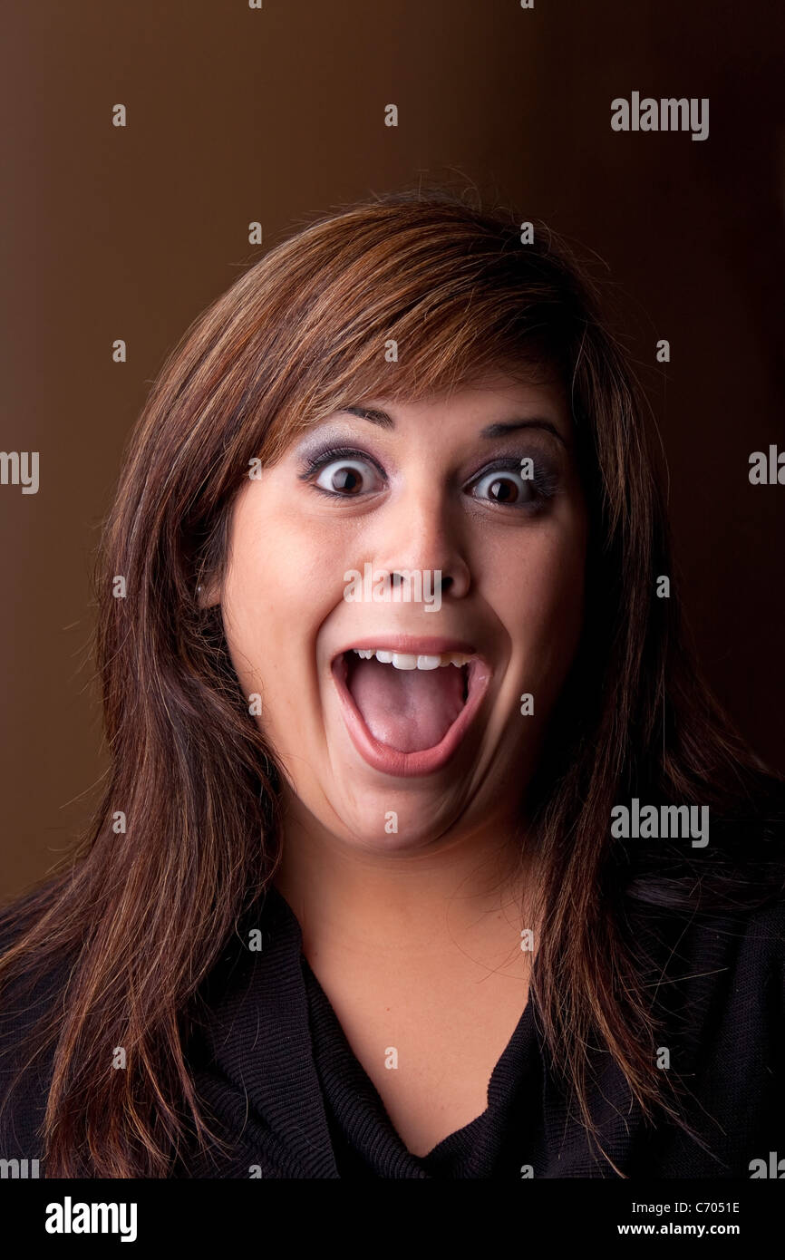 Woman with a funny look on her face smiles over a dark background. Stock Photo