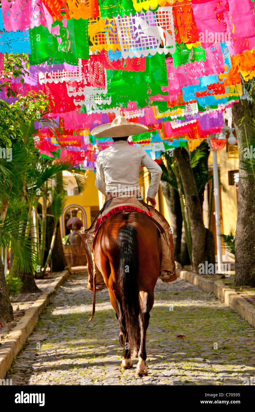 Cowboy (charro) riding horse on cobble stone street during celebration, Mexico. Stock Photo