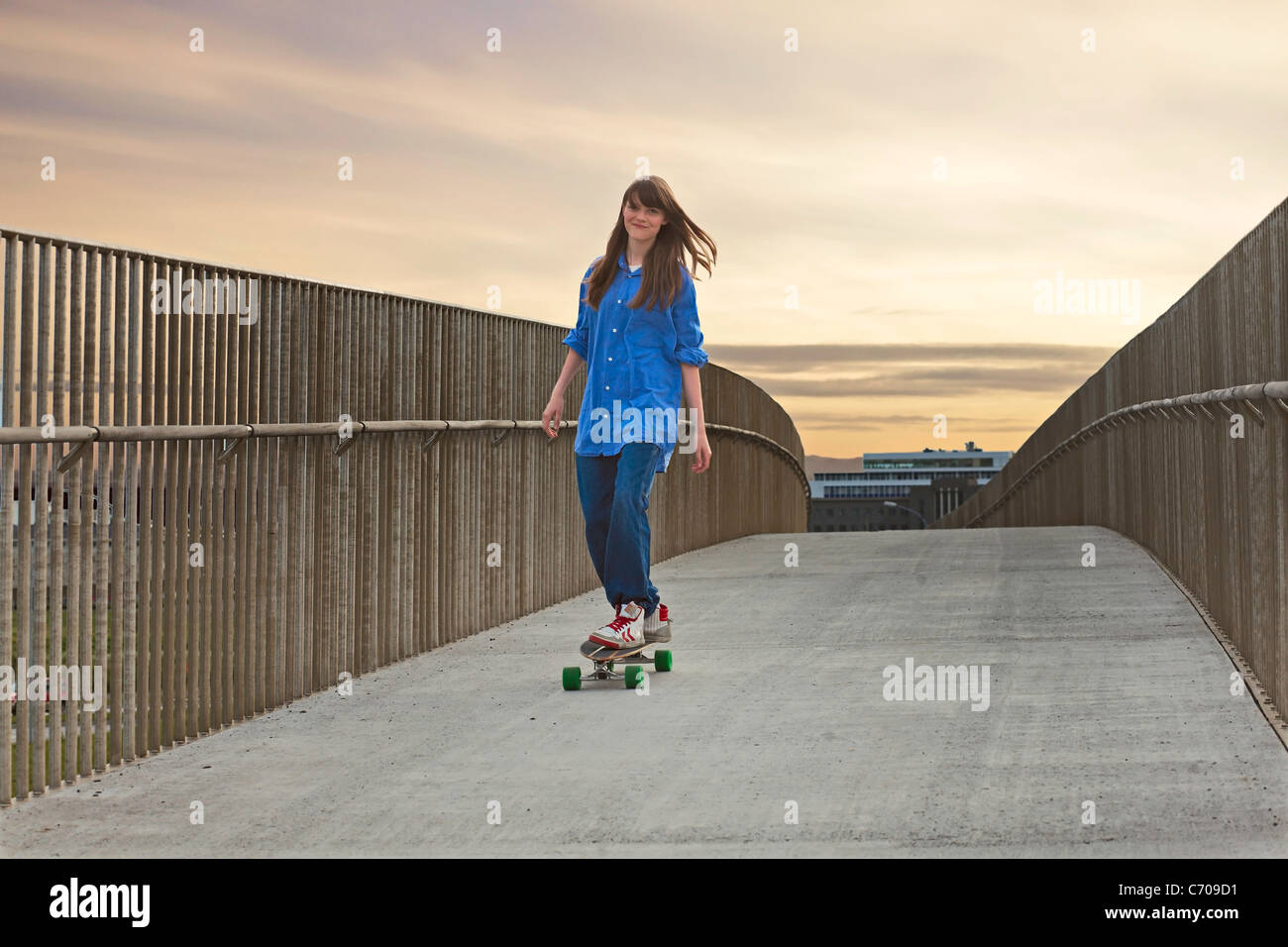 Girl riding skateboard on walkway Stock Photo