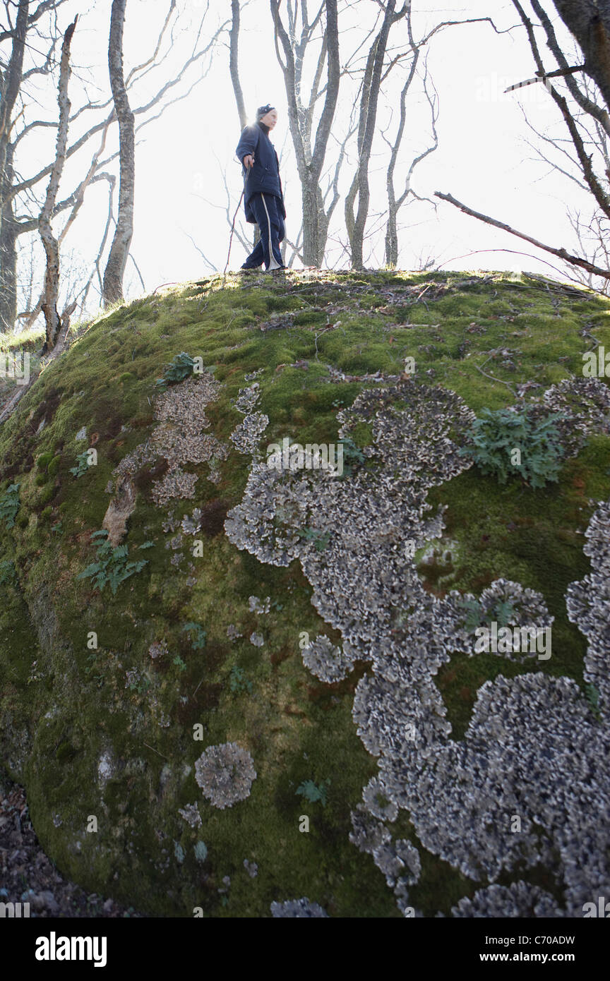 Man climbing mossy boulder Stock Photo