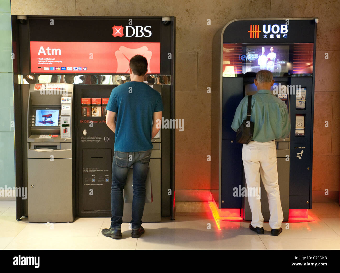 Two men getting cash from a DBS ATM and a UOB ATM, Ion mall, Singapore asia Stock Photo