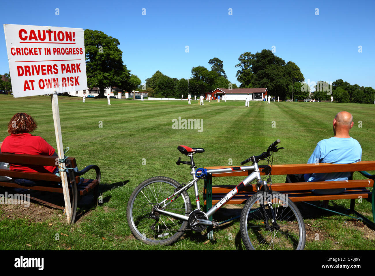 Sign warning drivers that they park next to the cricket ground at their own risk while a match is in progress, Southborough Common, Kent, England Stock Photo