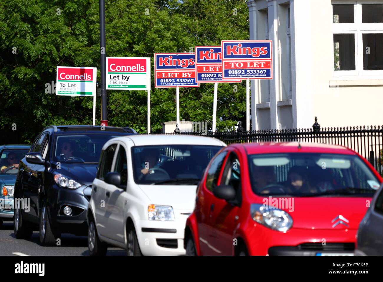 Row of To Let and Let By signs and traffic queue in street, Tunbridge Wells, Kent  England Stock Photo