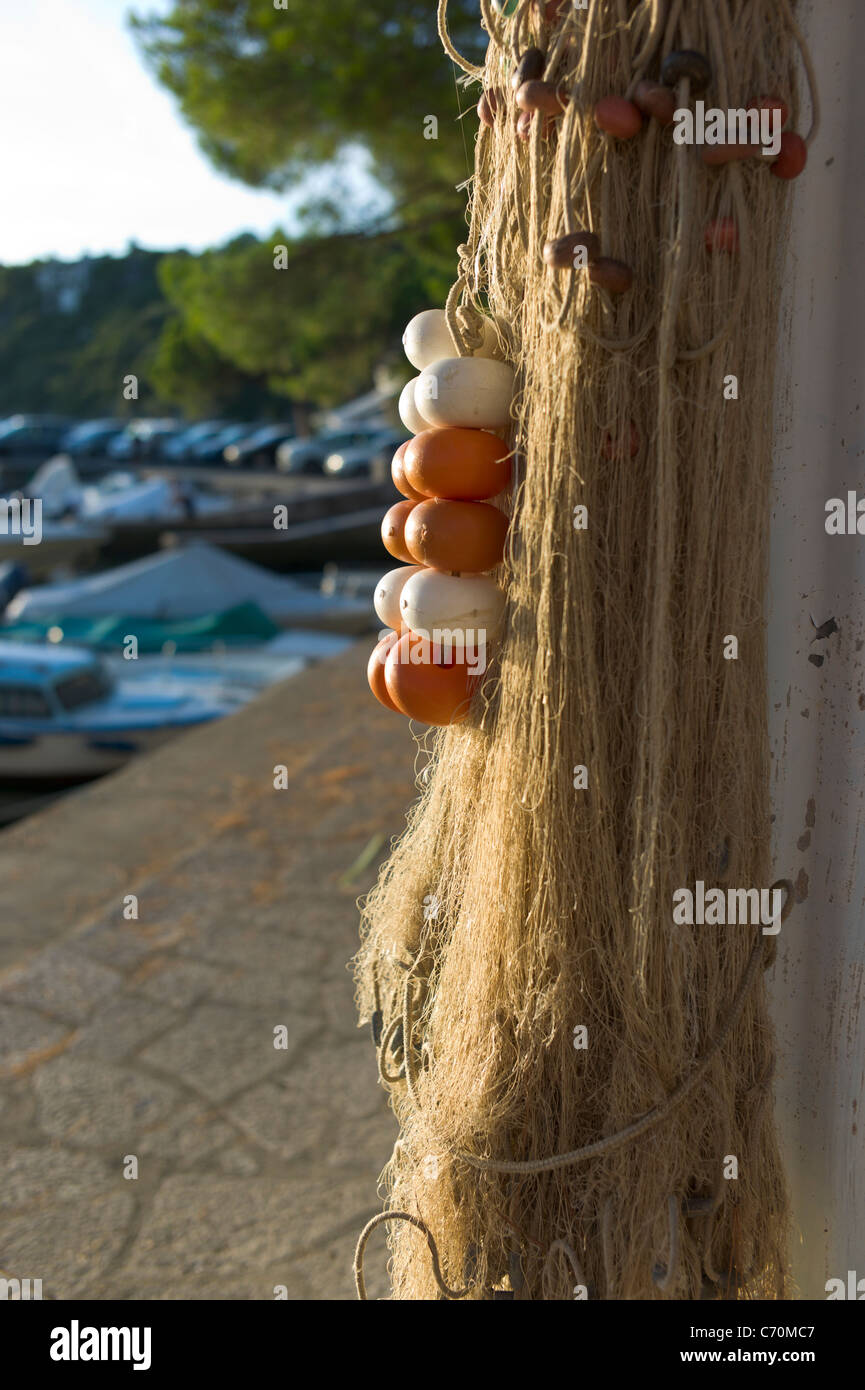 Fishing nets hung up for drying in, lit by the setting sun, Duino harbor, Italy Stock Photo