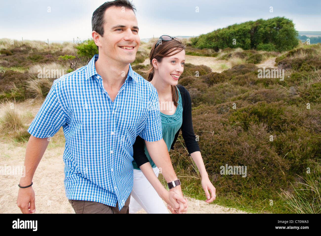 Couple walking hand-in-hand on beach Stock Photo