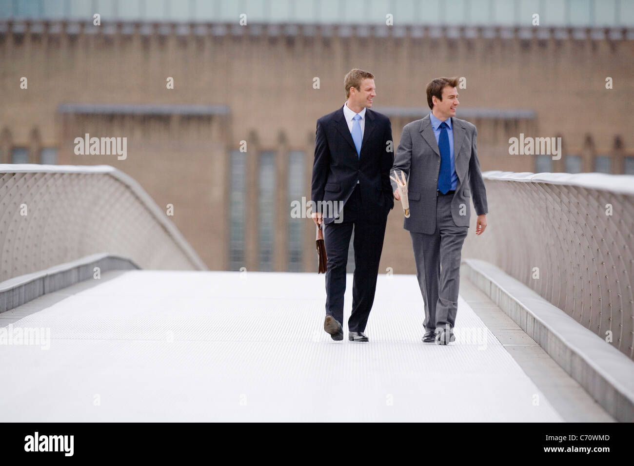 Businessmen walking on bridge together Stock Photo - Alamy