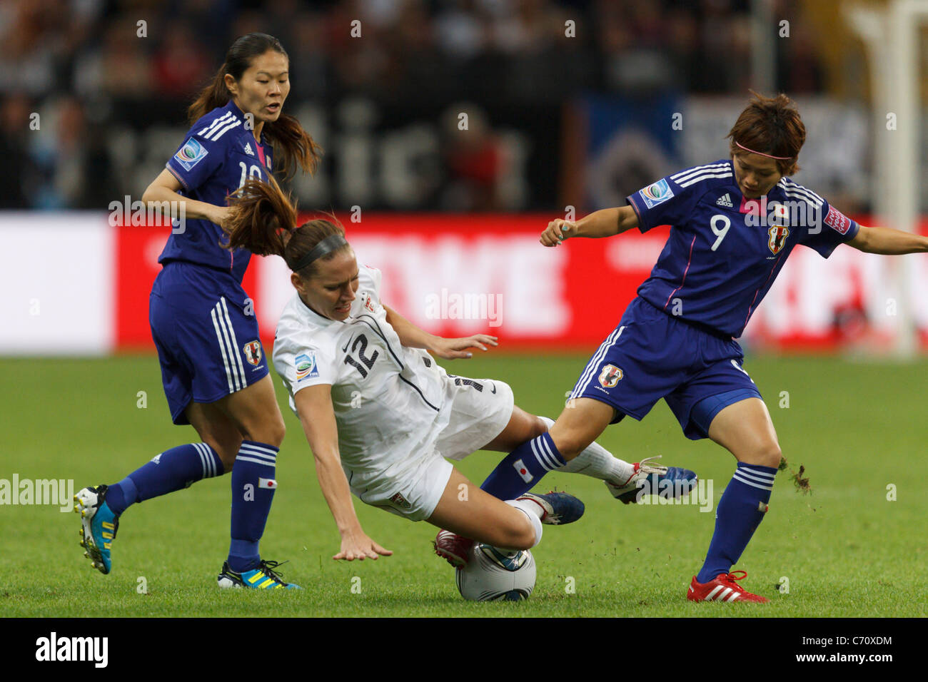 Lauren Cheney of the USA (12) goes down between Homare Sawa (l) and Nahomi Kawasumi (r) of Japan during the 2011 World Cup final Stock Photo