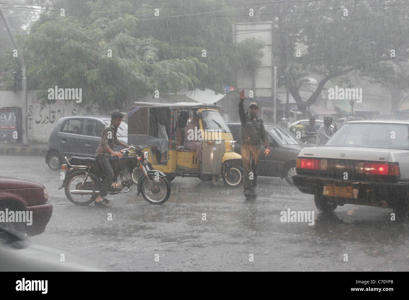 Traffic Warden control traffic at a road during heavy downpour of monsoon season in Karachi Stock Photo