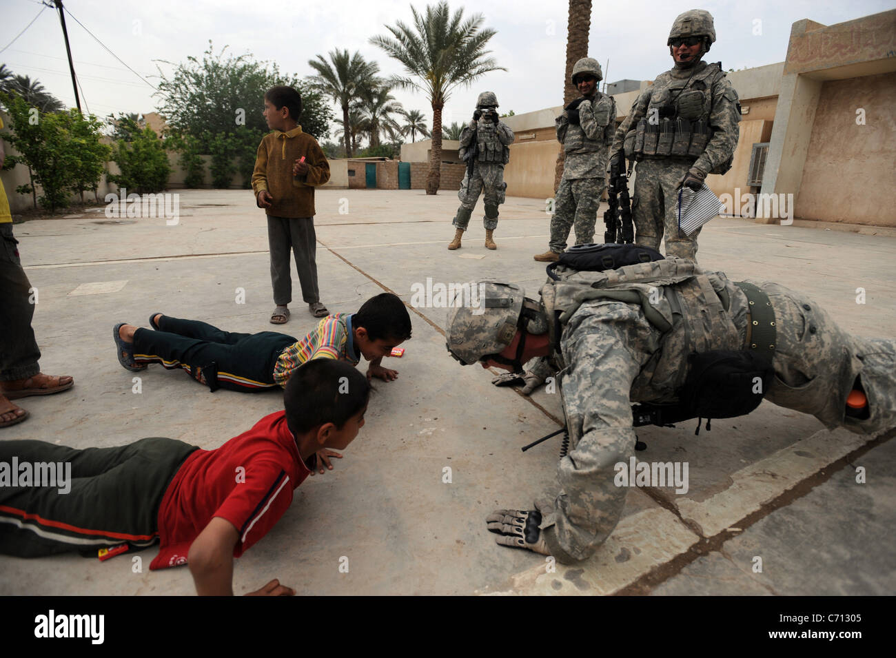 U.S. Army Staff Sgt. Josh Hedetniemi does pushups to amuse Iraqi children outside a school near Sheik Hammad, Iraq, on April 8, 2009. Hedetniemi is from Alpha Company, 1st Battalion, 111th Infantry Regiment, 56th Stryker Brigade Combat Team, 28th Infantry Division. DoD photo by Sgt. Jacob H. Smith, U.S. Army. (Released) Stock Photo