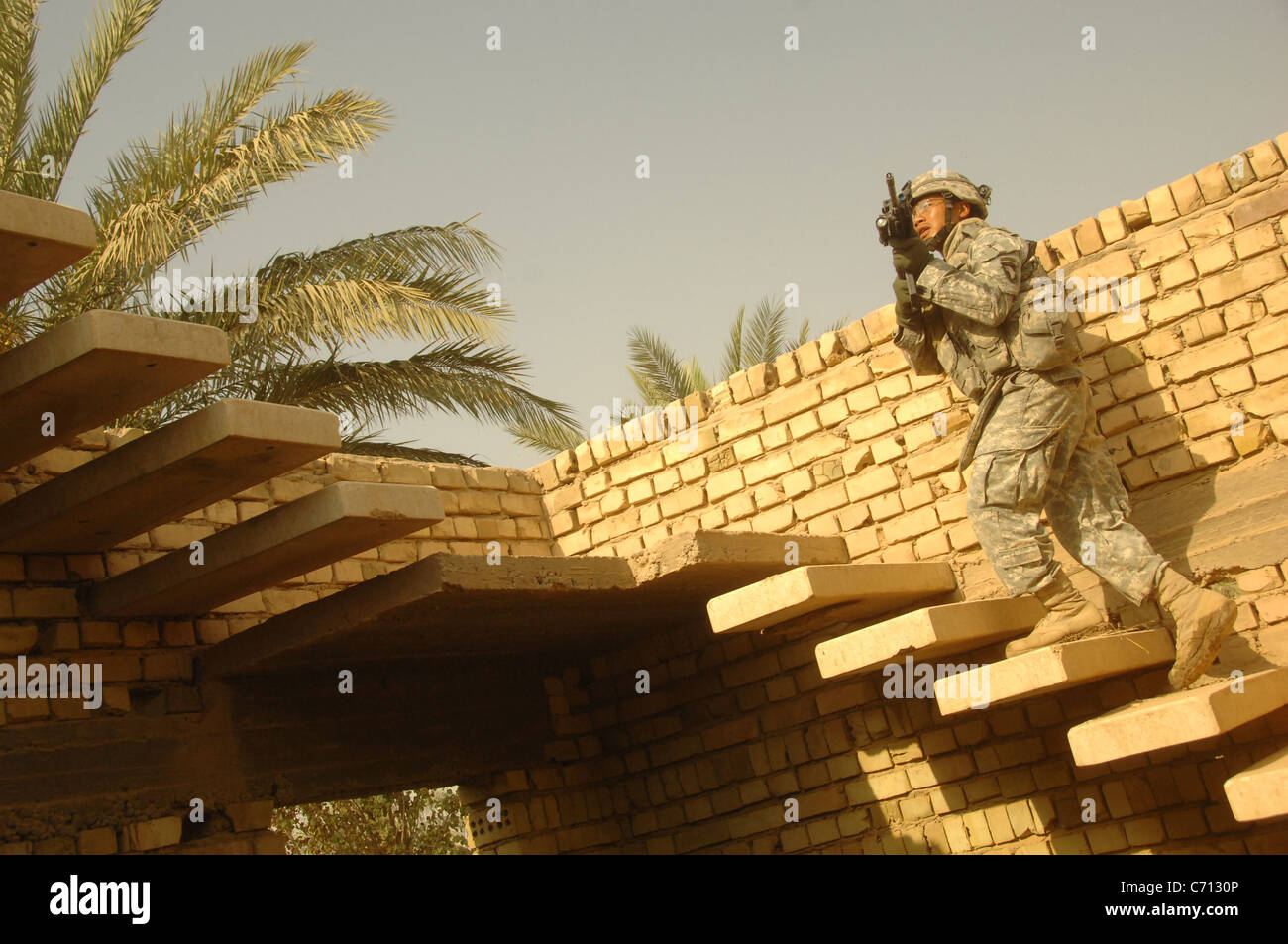 U.S. Army Sgt. Duong Tran moves to a roof top to provide security for other soldiers as they search the roof of a suspect house for hidden weapons caches during a search and cordon patrol in the city of Al Mahmudiyah, Al Mahmudiyah district, Baghdad province, Iraq, on Sept. 4, 2008. Tran is assigned to the 3rd Battalion, 320th Field Artillery Regiment, 3rd Brigade Combat Team, 101st Airborne Division (Air Assault). DoD photo by Spc. Richard Del Vecchio, U.S. Army. (Released) Stock Photo