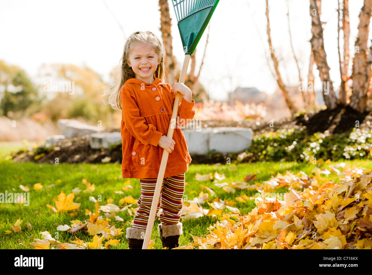 Cute girl holding rake Stock Photo - Alamy