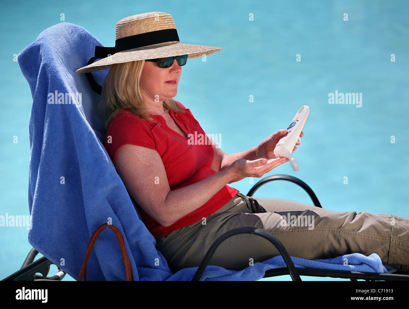 Putting on suntan lotion pool side Stock Photo Alamy