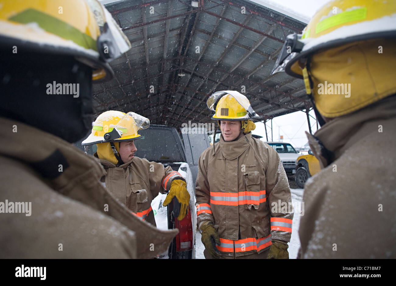 firefighters encircle another firefighter who is talking Stock Photo