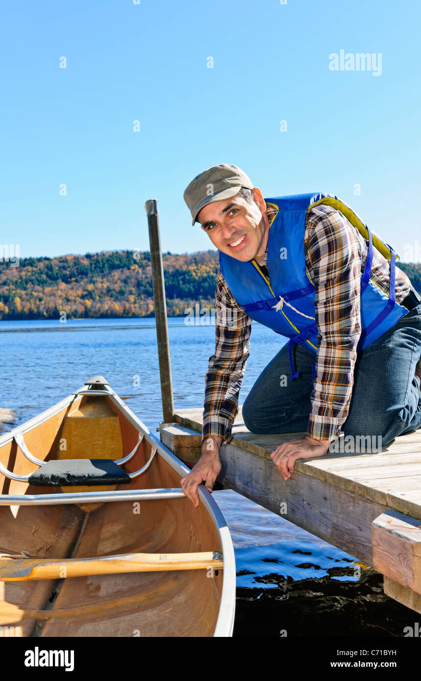 Man holding canoe at dock on Lake of Two Rivers, Ontario, Canada Stock Photo