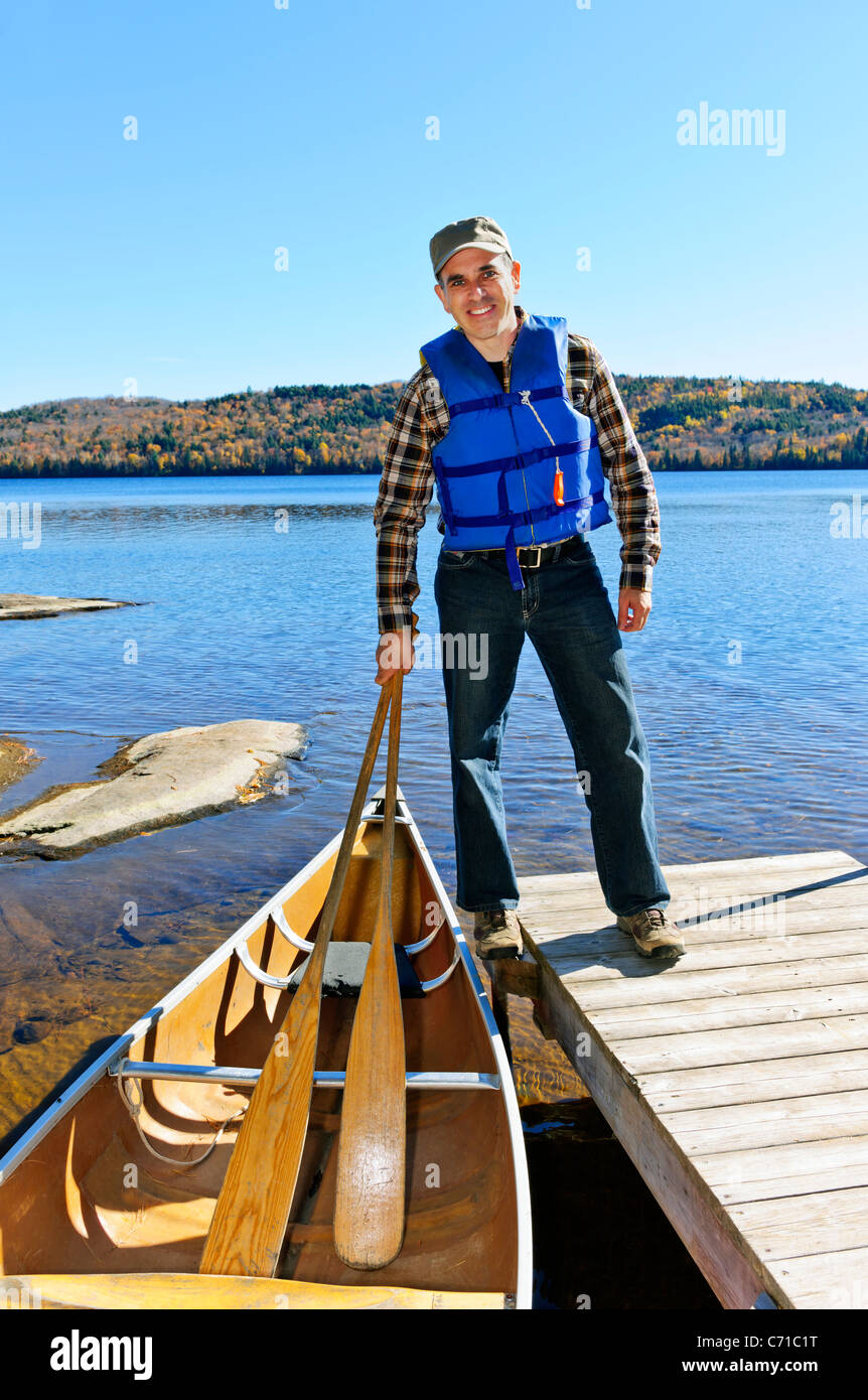Man standing on dock with canoe on Lake of Two Rivers, Ontario, Canada