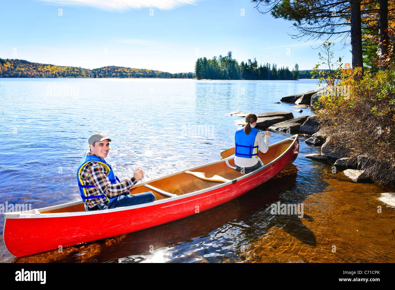 Family in red canoe near rocky shore of Lake of Two Rivers, Ontario