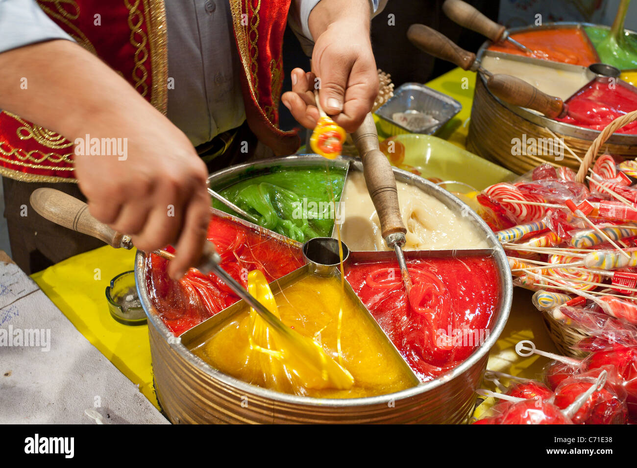 Candy making in the market. Hands move swiftly rolling the molten multicoloured candy into mouth watering suckers Stock Photo