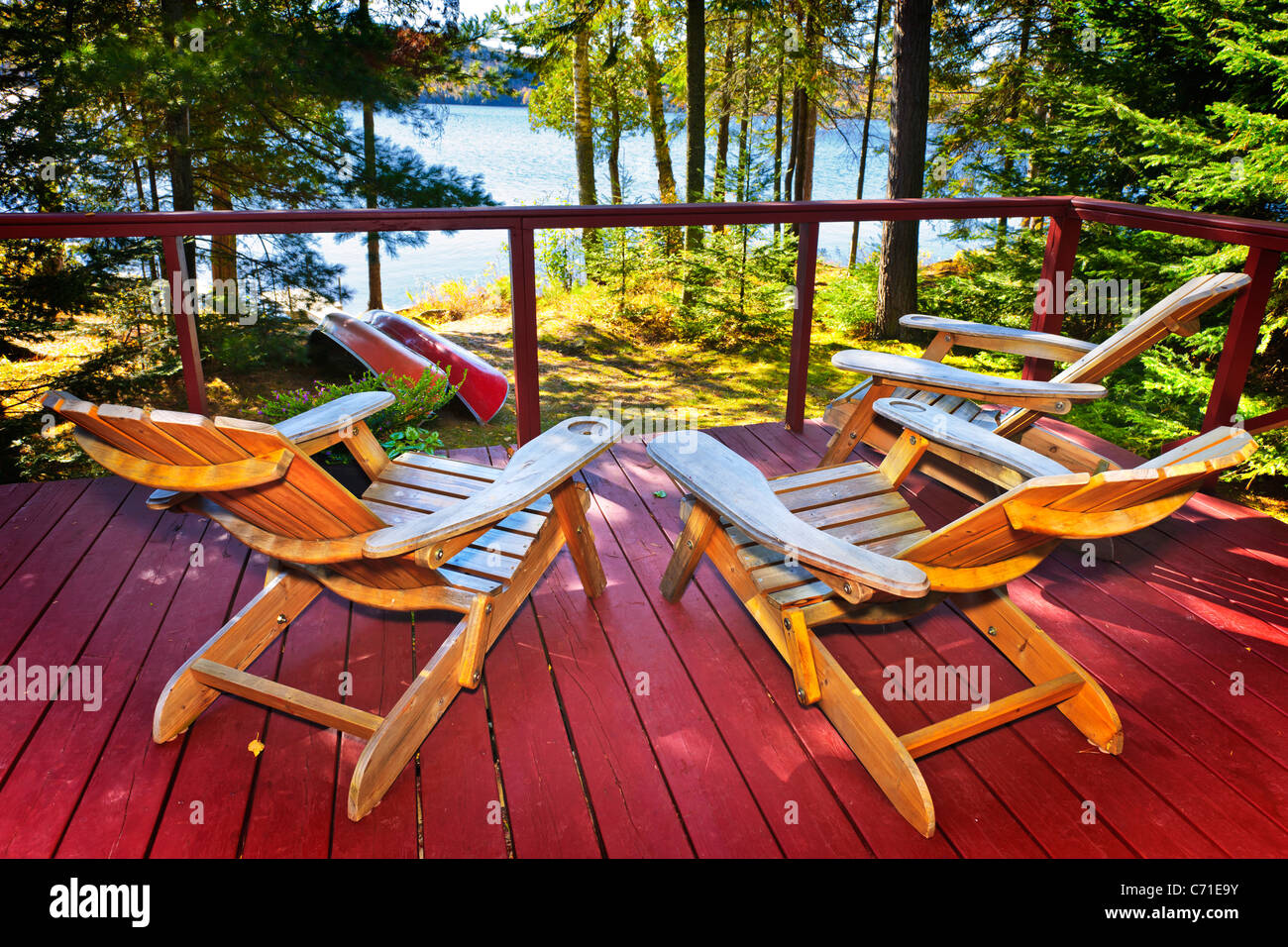 Wooden deck of cottage with Adirondack chairs at lake Stock Photo