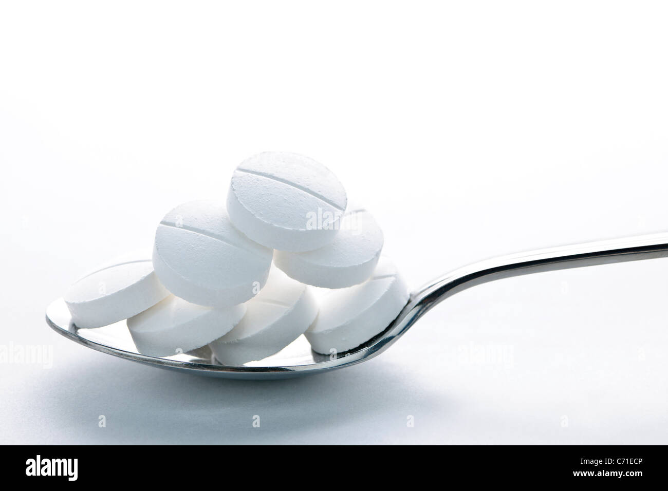 Calcium supplement pills piled on metal spoon closeup Stock Photo