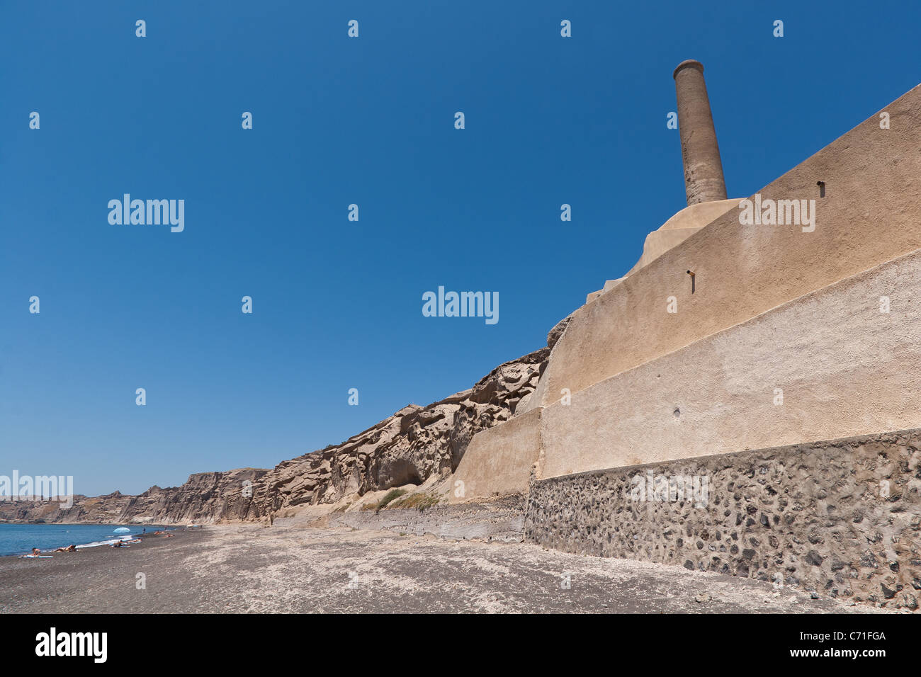 disused factory and volcanic rocks along the beach at Vlychada, Santorini Stock Photo