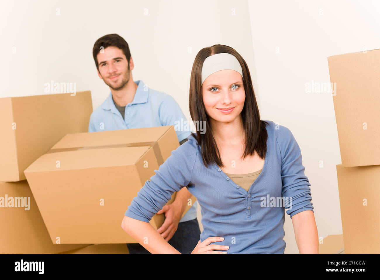 Happy young couple moving into new home carrying cardboard boxes Stock ...