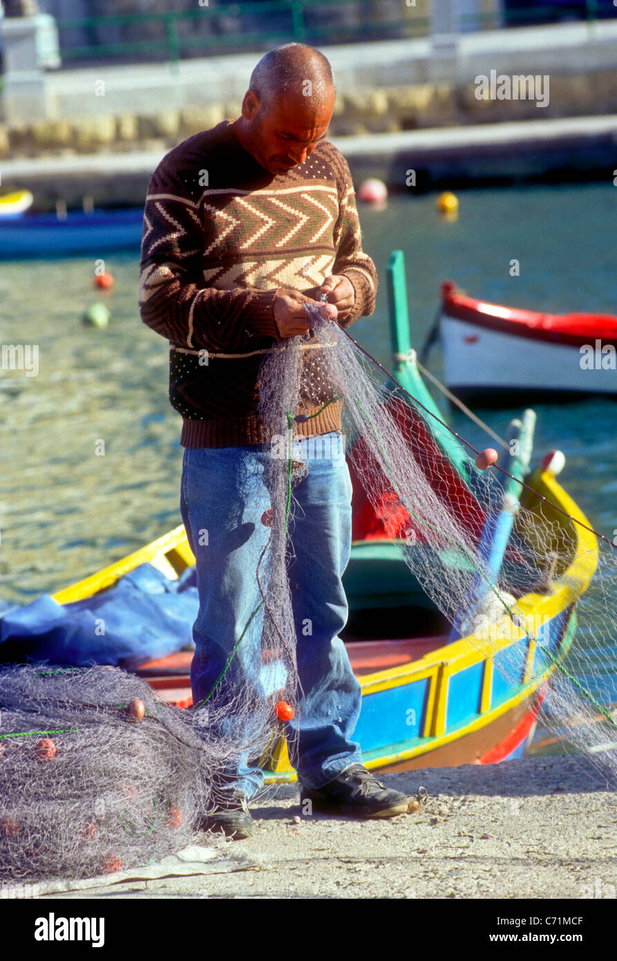 Fisherman with fishing nets, St Julian's Bay, Malta Stock Photo Alamy
