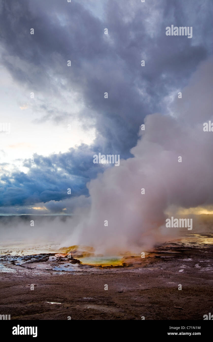 The Clepsydra Geyser erupts at sunset in the Lower Geyser Basin of Yellowstone National Park, Wyoming. Stock Photo