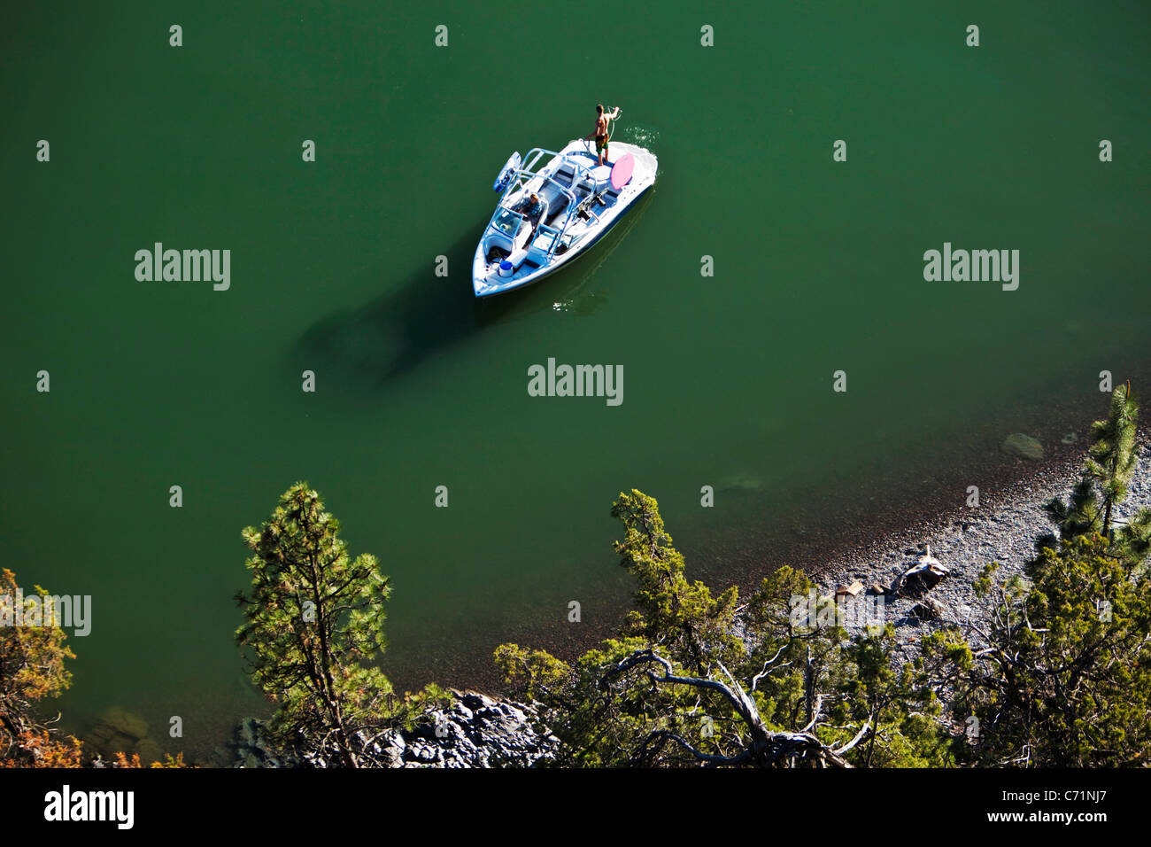 A man coils his wakeboard rope as his sexy girlfriend drives the boat. Shot from above in Idaho. Stock Photo