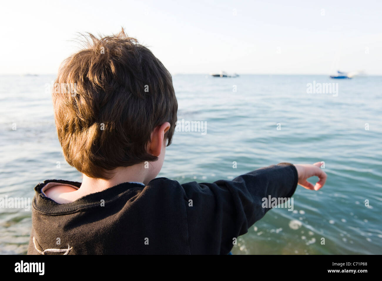 Boy looking at ocean view, pointing Stock Photo