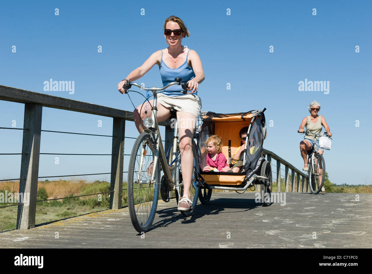 Multigeneration family enjoying bicycle ride, children sitting in bicycle trailer Stock Photo