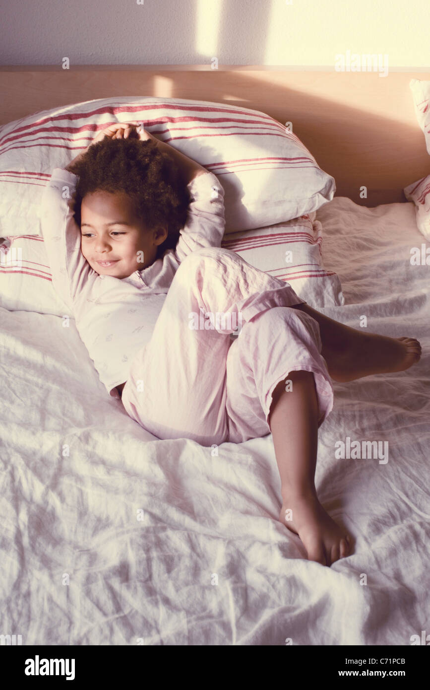 Little girl lying on bed in pajamas Stock Photo - Alamy
