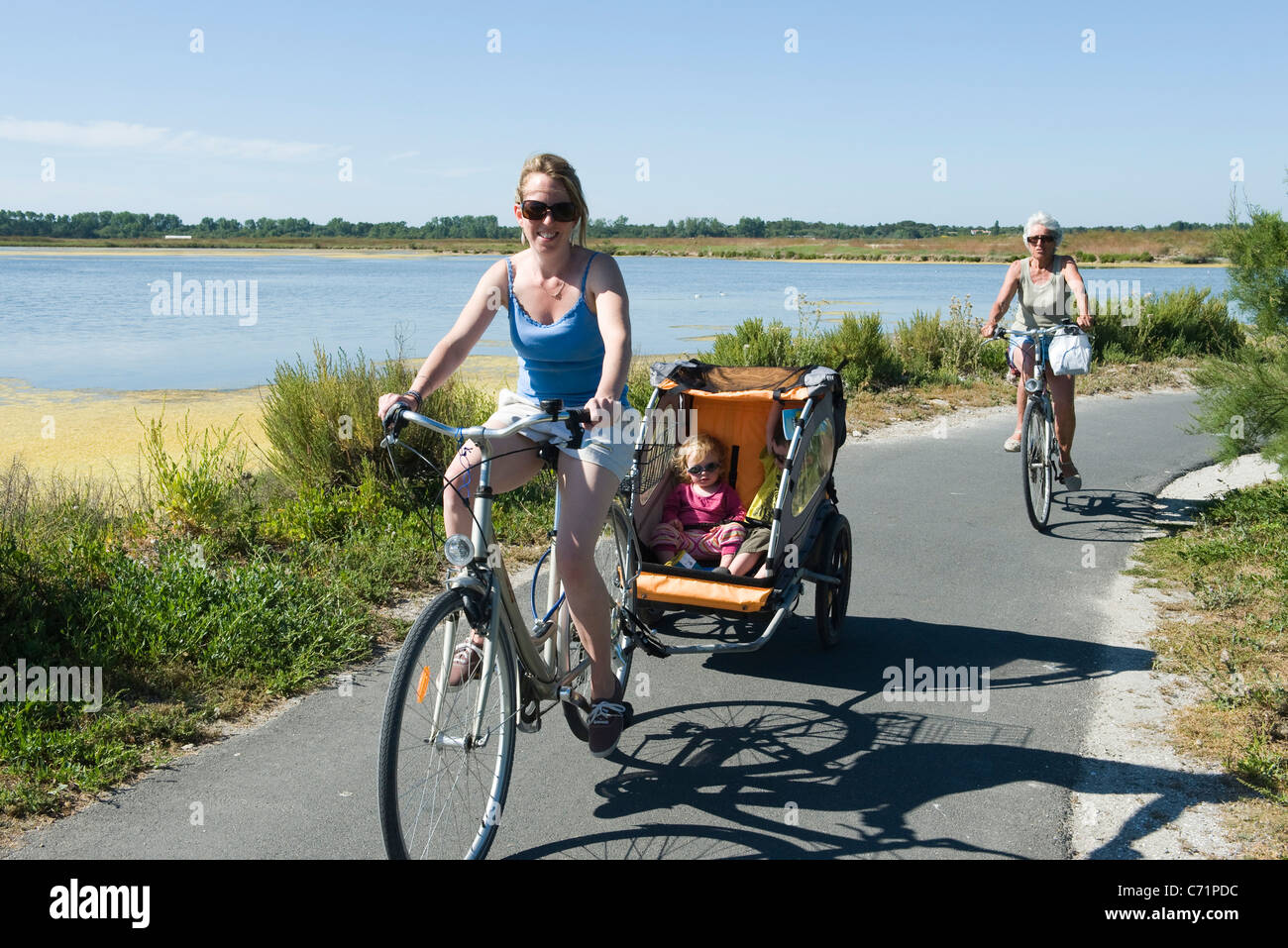 Multigeneration family enjoying bicycle ride, children sitting in bicycle trailer Stock Photo