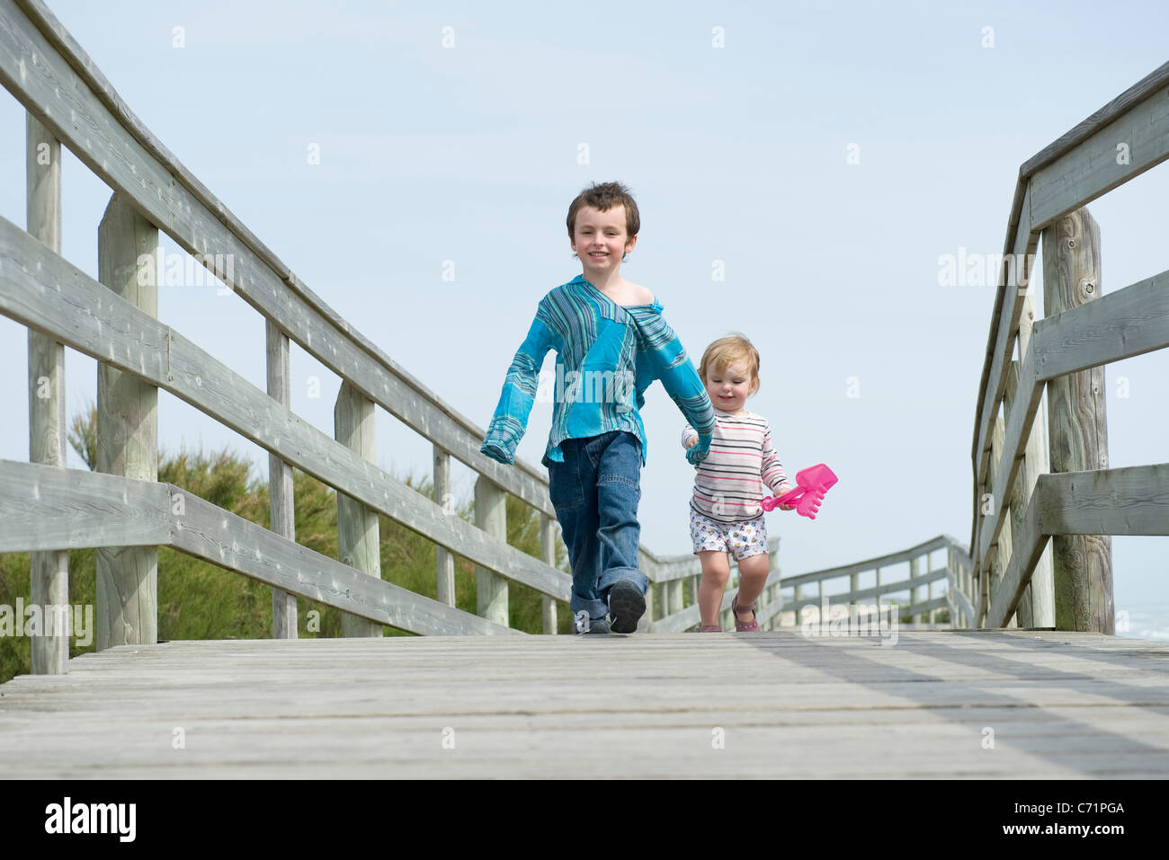 Young siblings walking hand in hand on boardwalk Stock Photo
