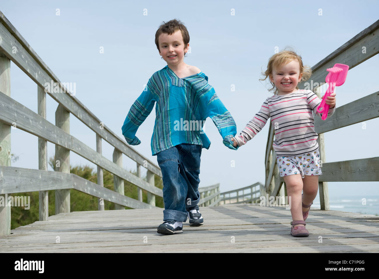 Young siblings walking hand in hand on boardwalk Stock Photo