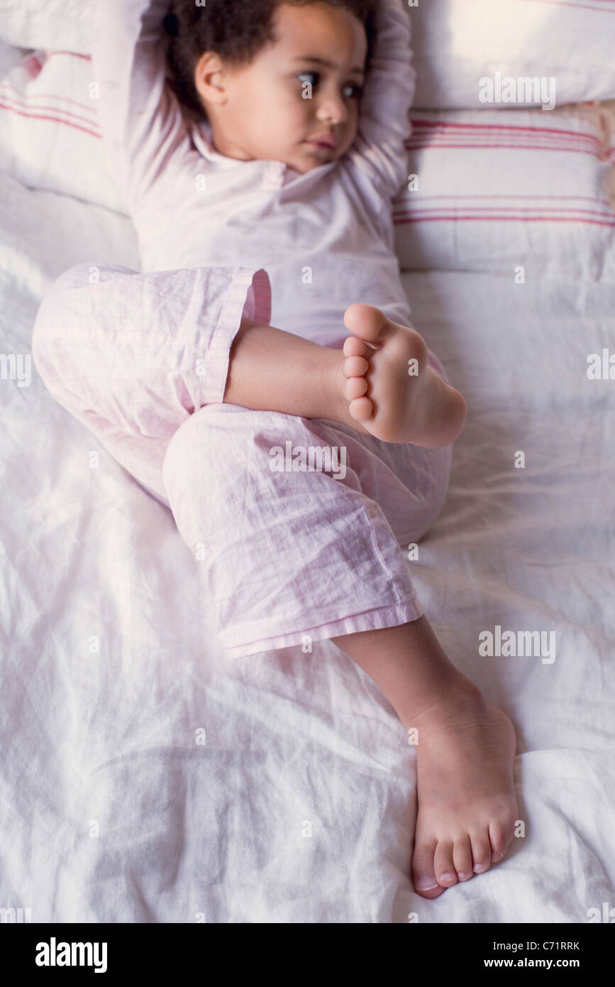 Little girl lying on bed in pajamas Stock Photo - Alamy