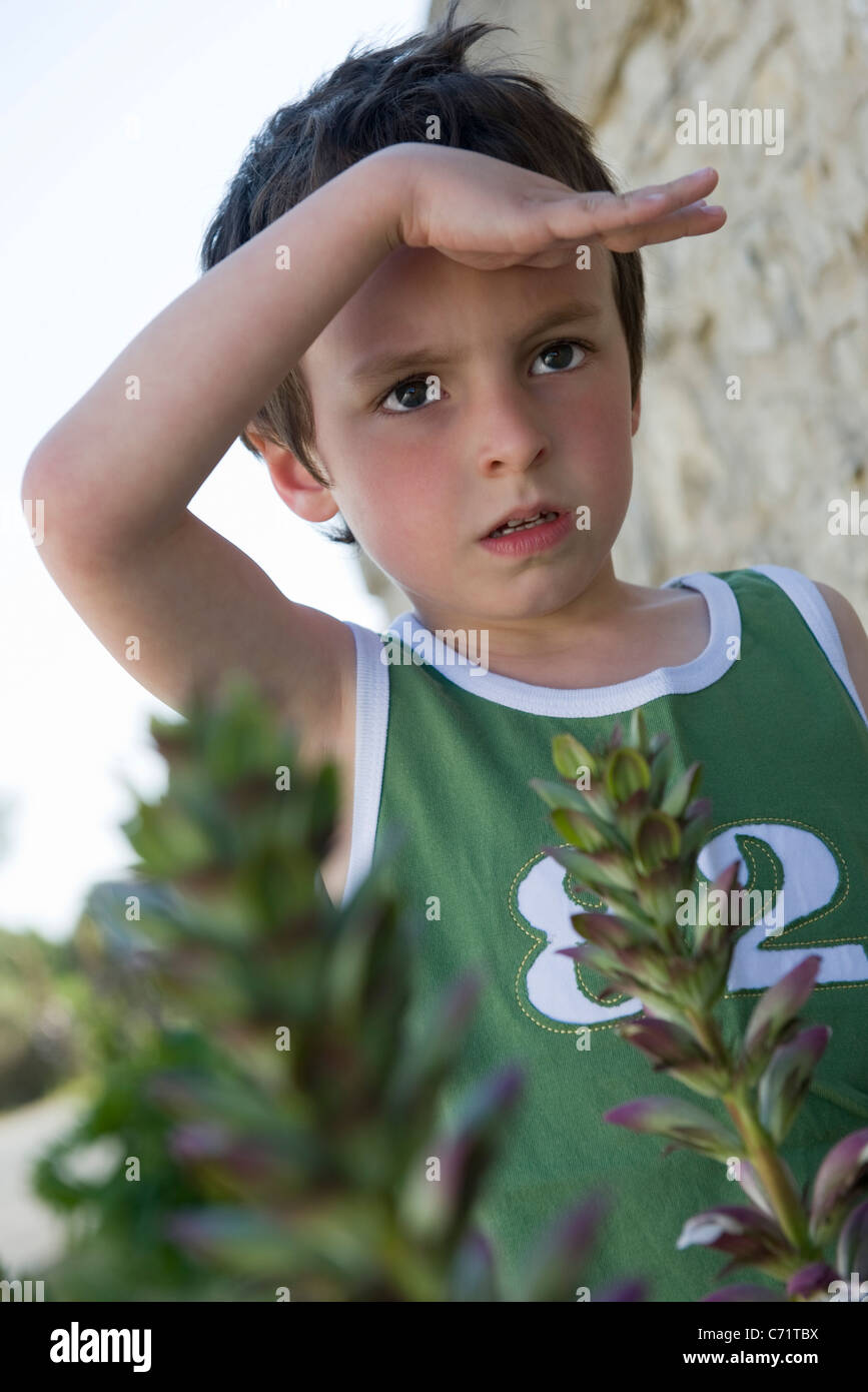 Boy looking at something out of frame, shading eyes with hand Stock Photo