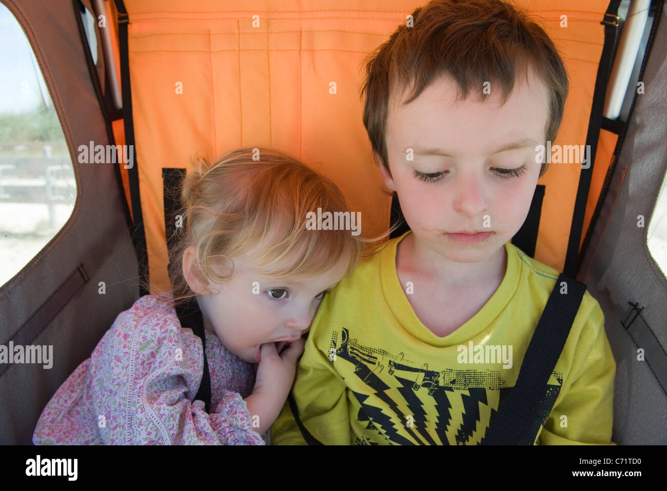 Brother and sister riding together in stroller Stock Photo - Alamy