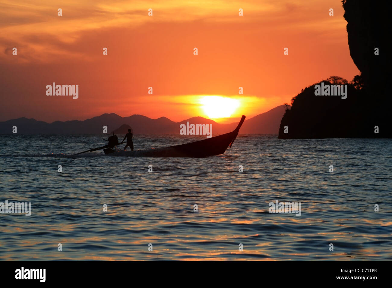 a long tail boat heads home at sunset, Krabi, Thailand Stock Photo