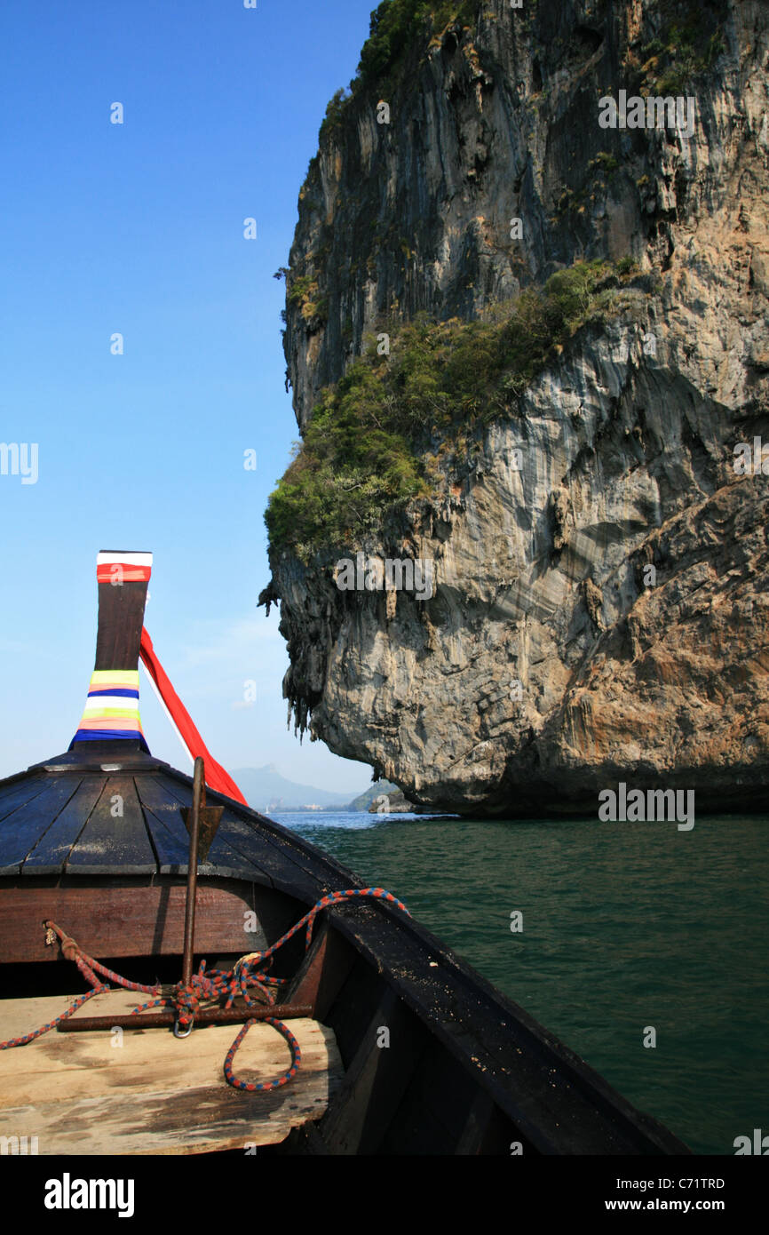 a Thai long tail boat prow as it passes a limestone cliff near Krabi, Thailand Stock Photo