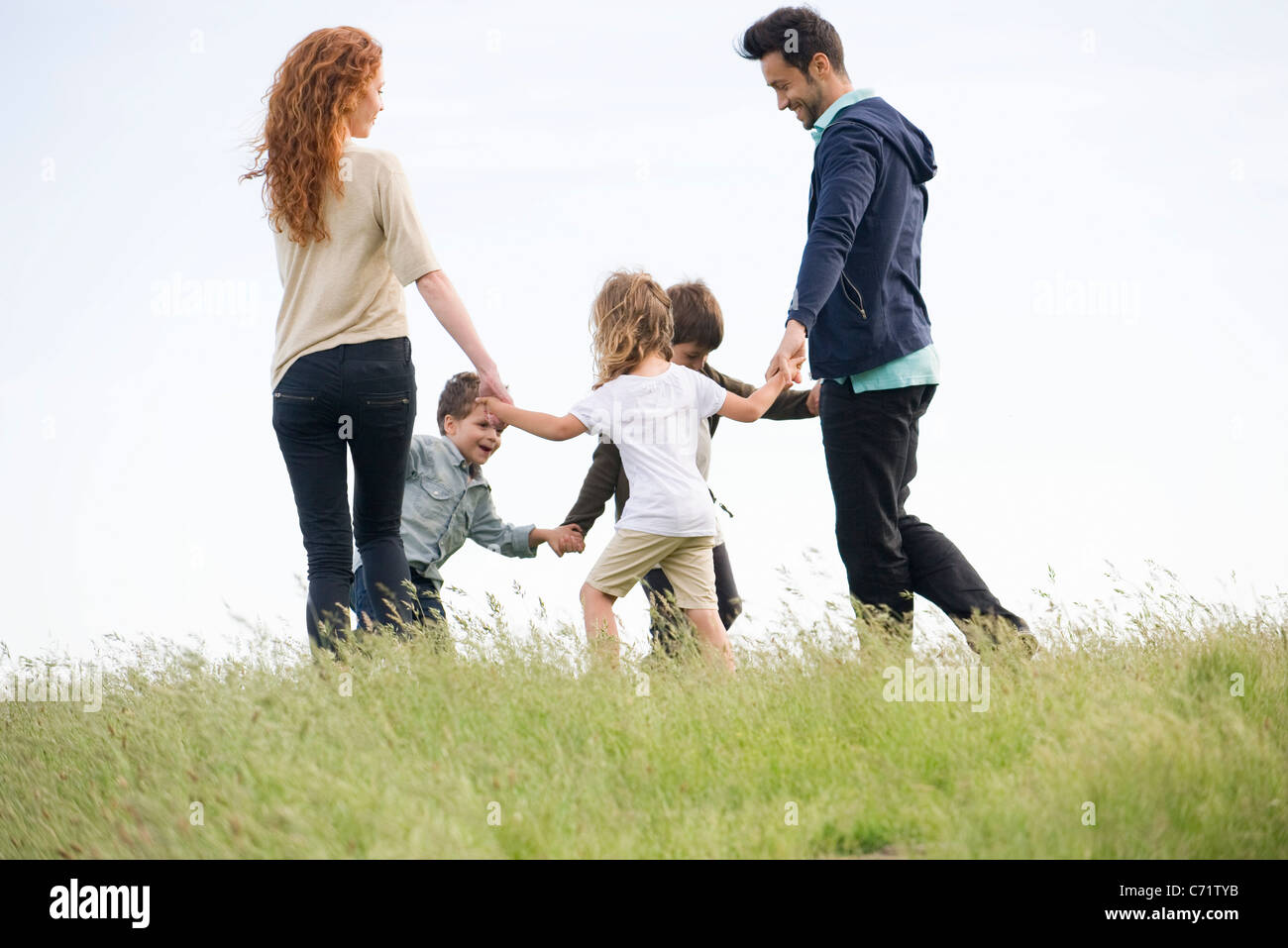 Family playing ring-around-the-rosy in meadow Stock Photo