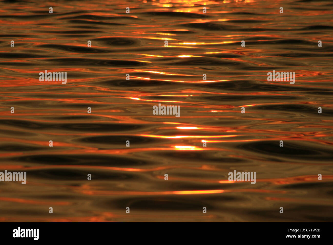 orange sunset reflected on water with ripple texture Stock Photo
