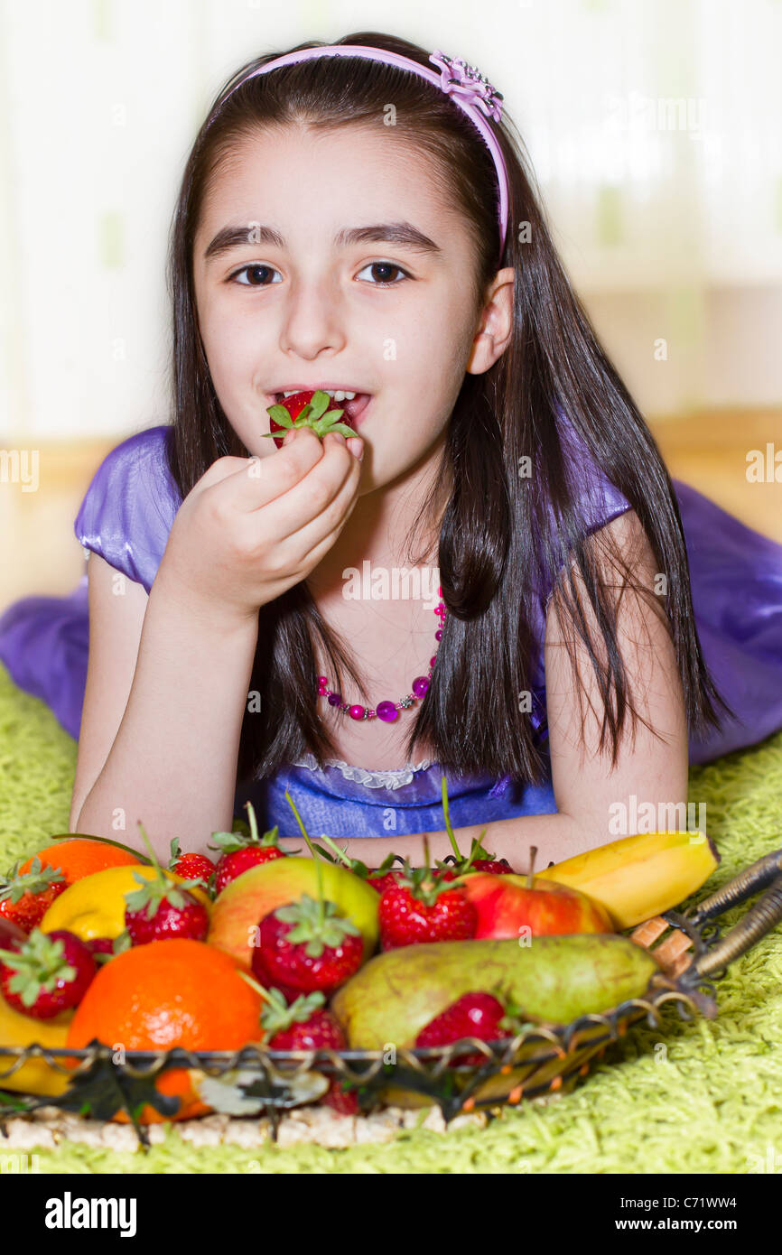 Little girl eating strawberry from a fruit basket Stock Photo