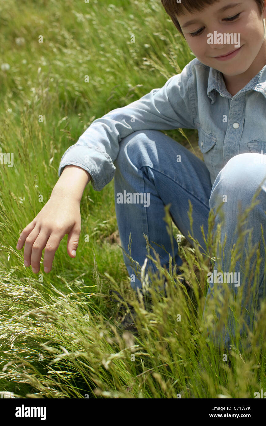 Boy sitting in grassy field Stock Photo Alamy