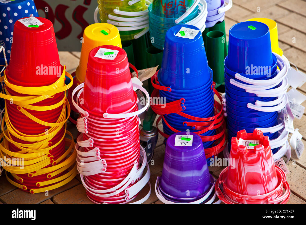Brightly coloured children's toy plastic beach buckets on display outside a seaside shop. Stock Photo