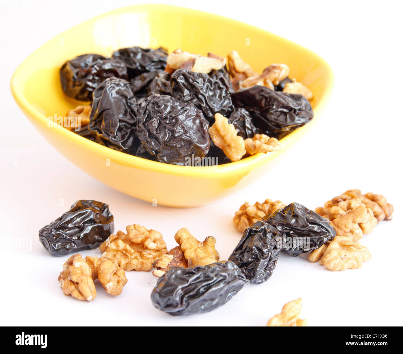 Prunes with nuts in bowl on white background Stock Photo