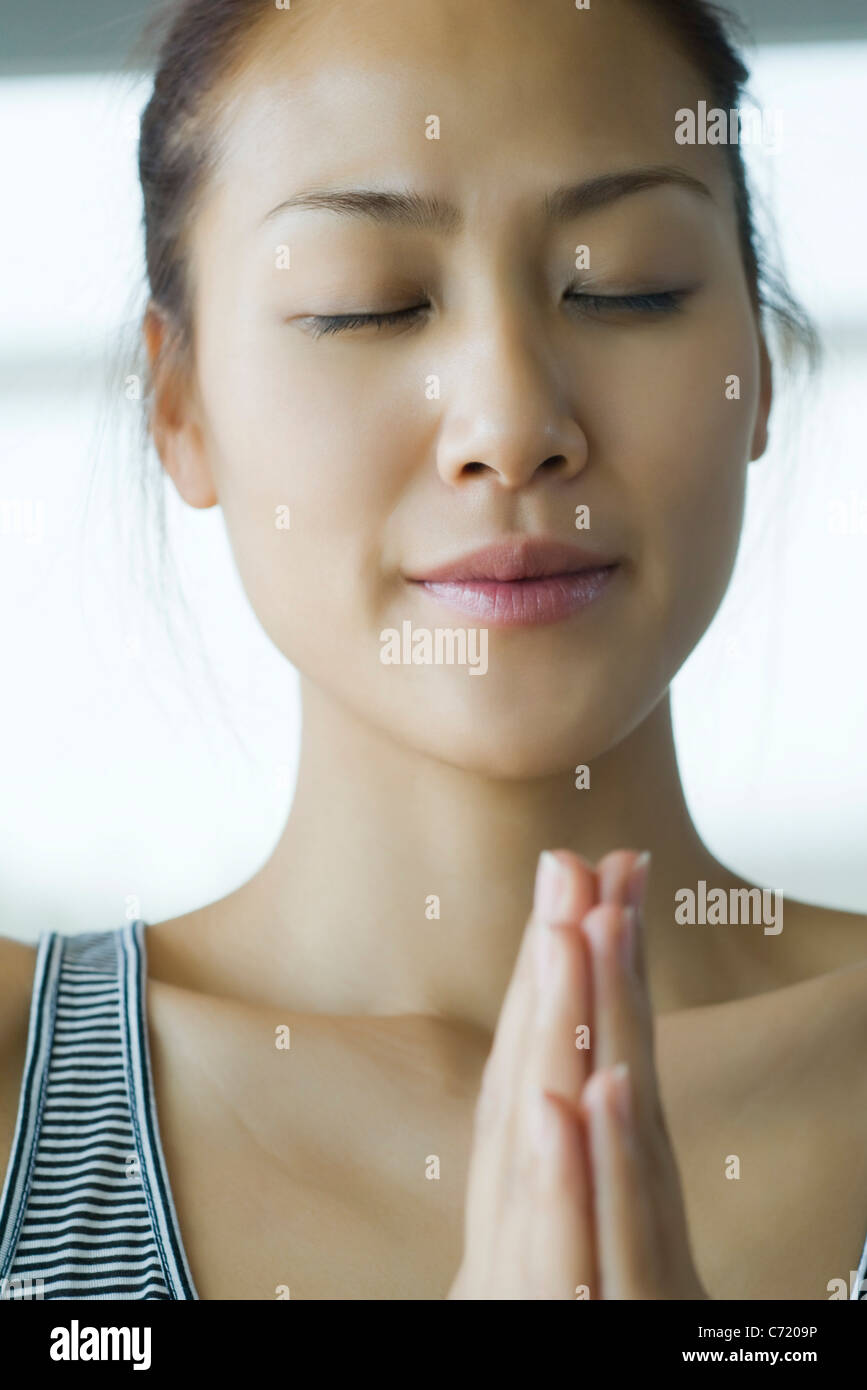 Young woman holding hands in prayer position Stock Photo - Alamy