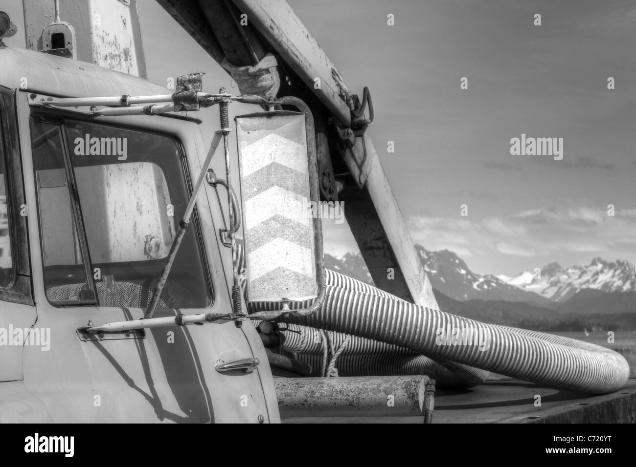 Crop of an old work truck in Alaska with mountains in the background, black and white. Stock Photo