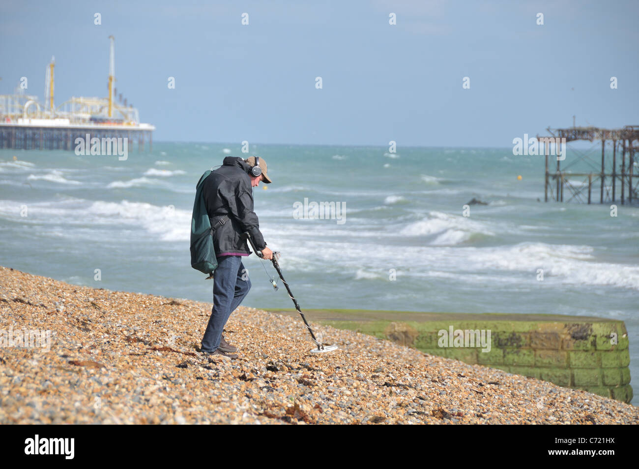 Man with metal detector on beach and brighton pier hires stock