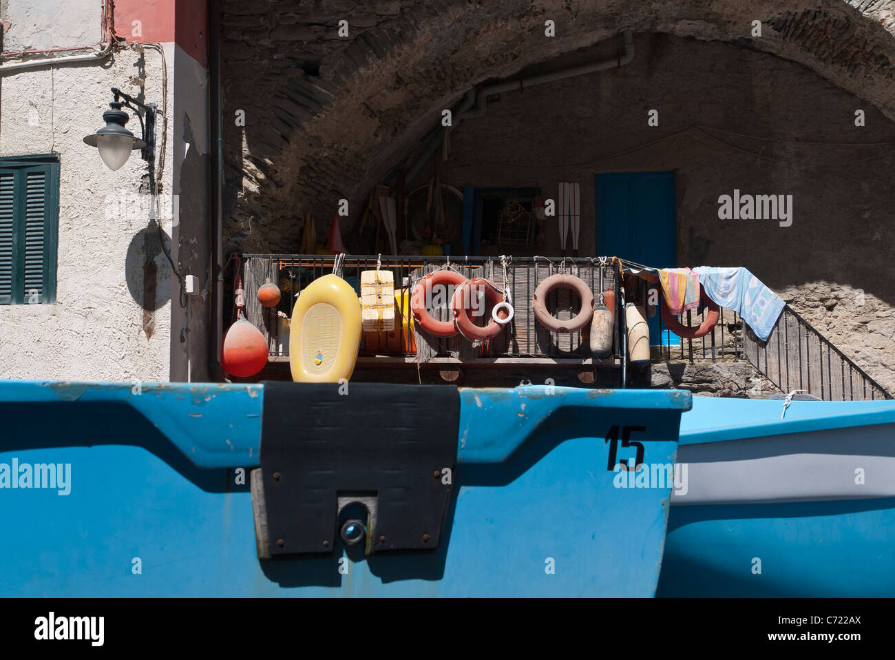 Boating accessories such as boat bumpers and life preservers hang from a railing with boats in foreground in Riomaggiore, Italy. Stock Photo
